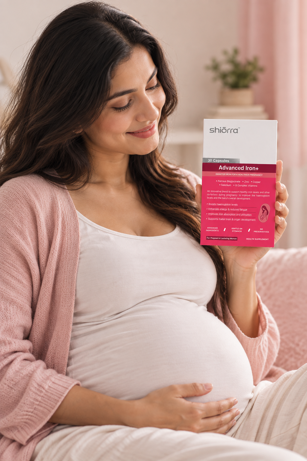 A pregnant woman smiling at a pack of Shiōrra Advanced Iron+ in her hand